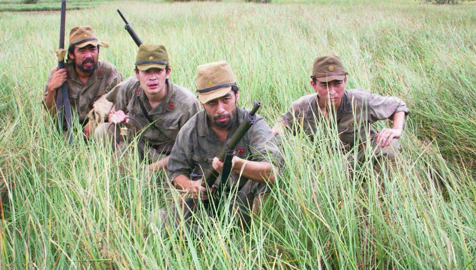 Des militaires accroupis dans des hautes herbes. Extrait du film 