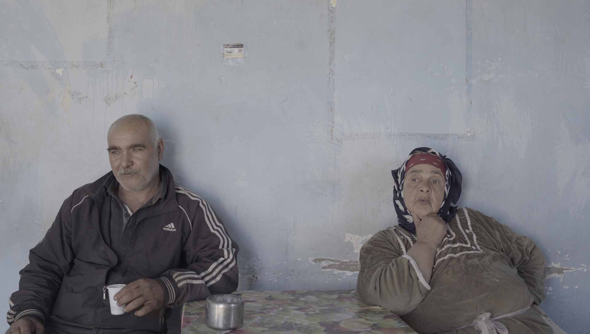 Un homme et une femme sont assis à une table. Extrait du film 143 Rue du désert de Hassen Ferhani