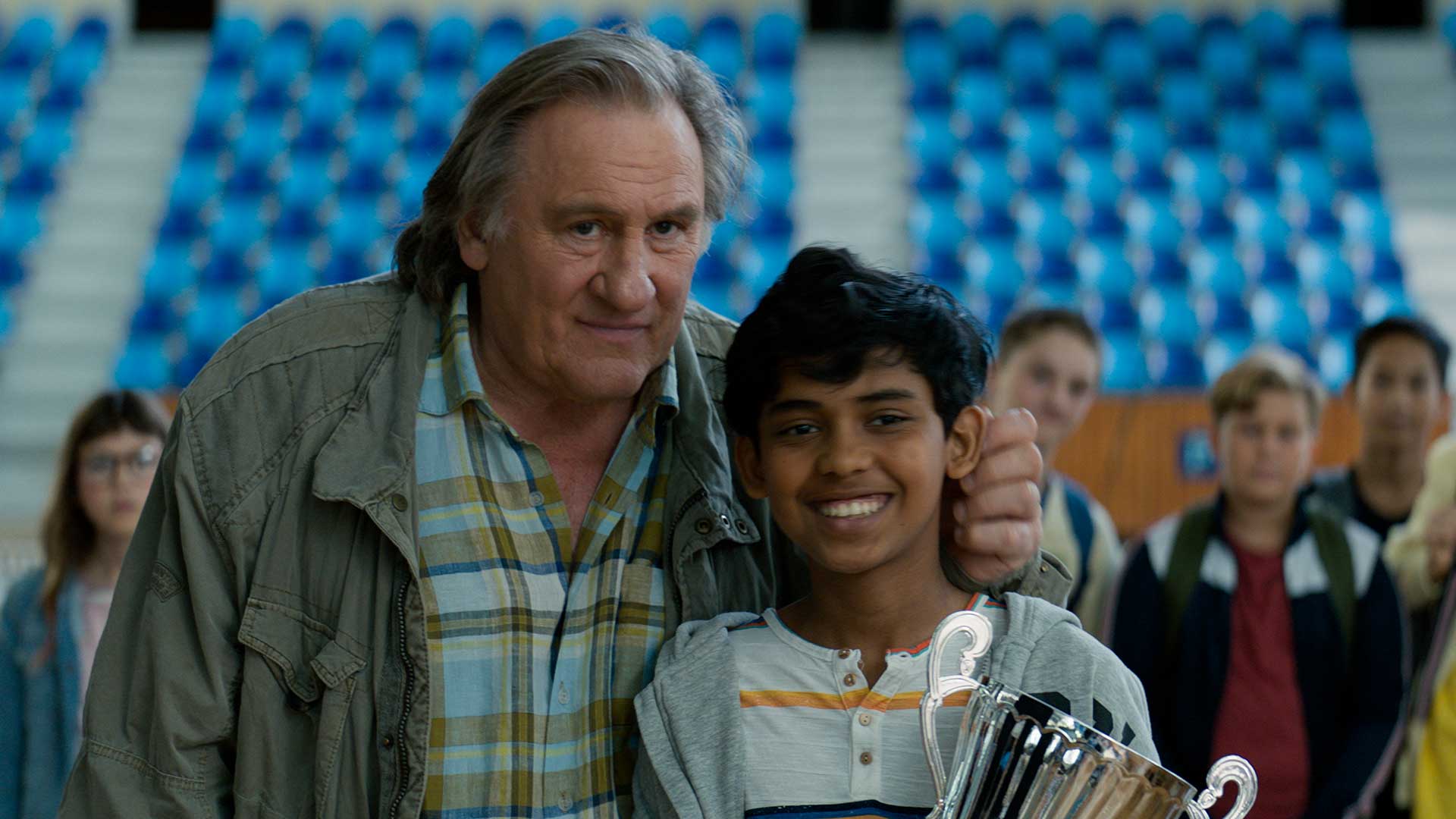 Un enfant sourit en tenant un trophée dans les mains.