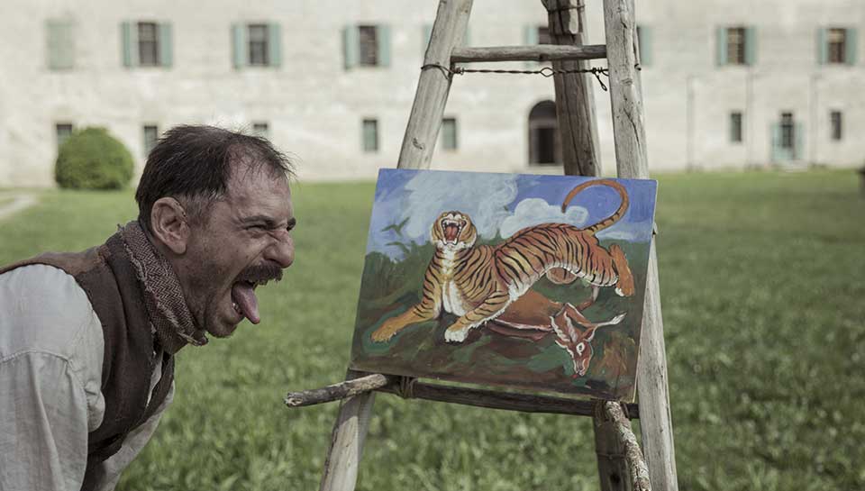Un homme tire la langue à un tableau représentant un tigre. Extrait du film 