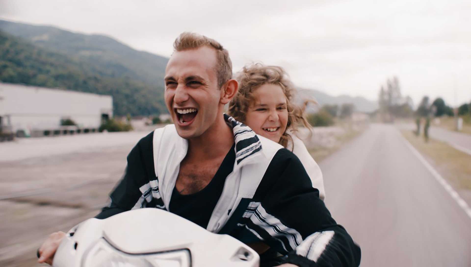 Un jeune adulte et une enfant roule à pleine vitesse sur un scooter