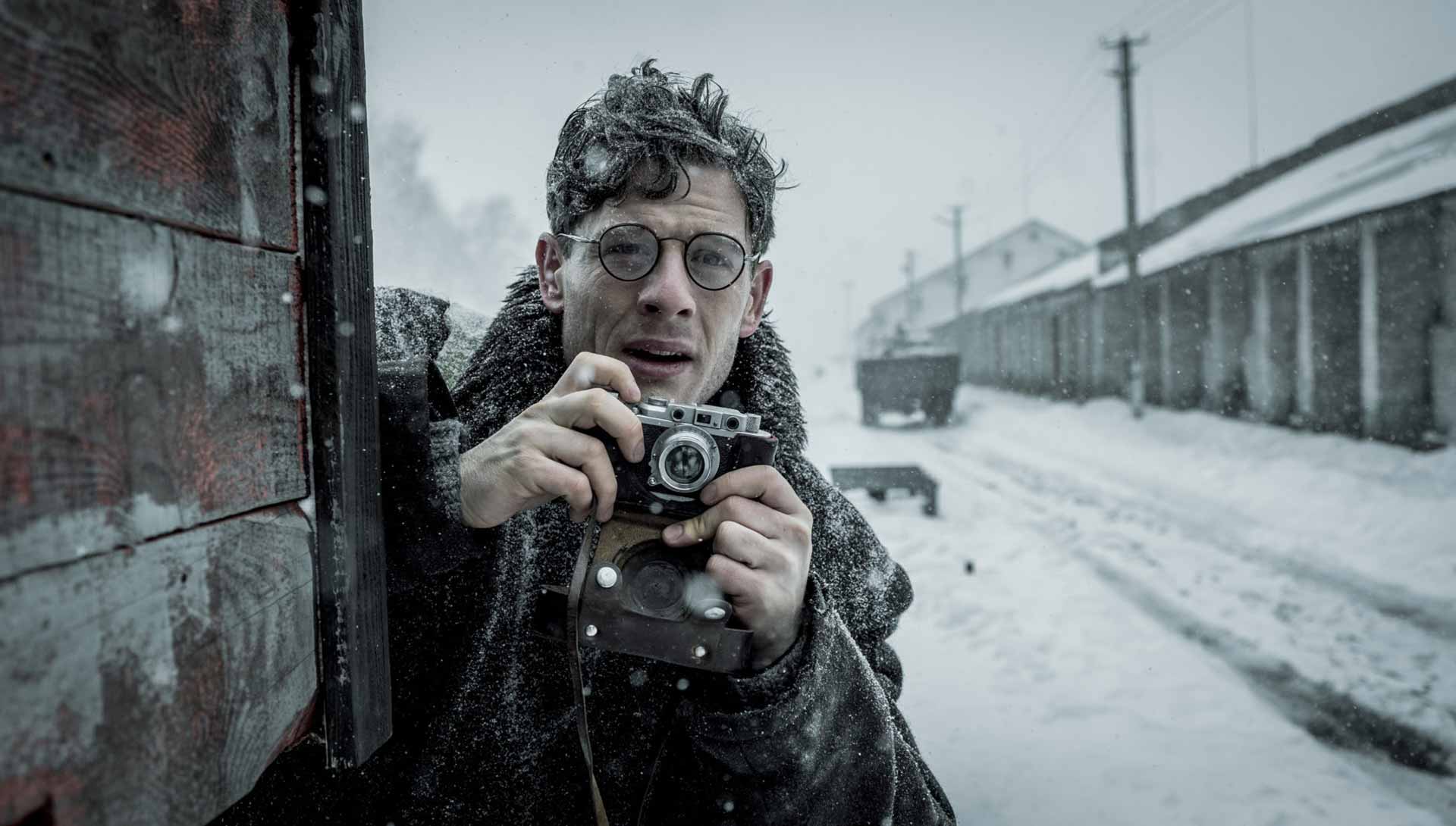 Un homme sous la neige tenant un appareil photo