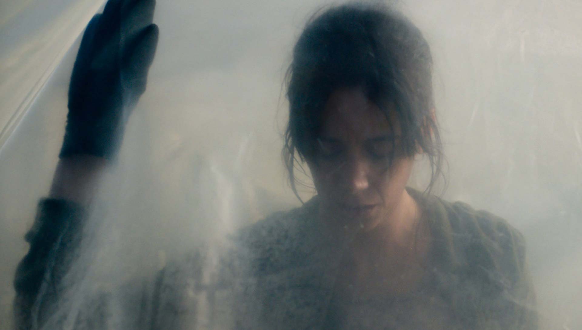 Une femme derrière une bache transparente. Extrait du film La Nuée de Just Philippot