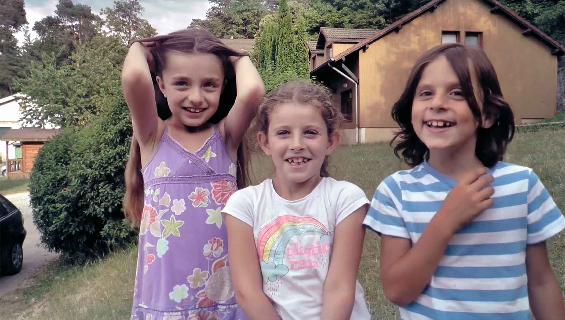 Trois enfants sourient à la caméra. Photogramme du documentaire 