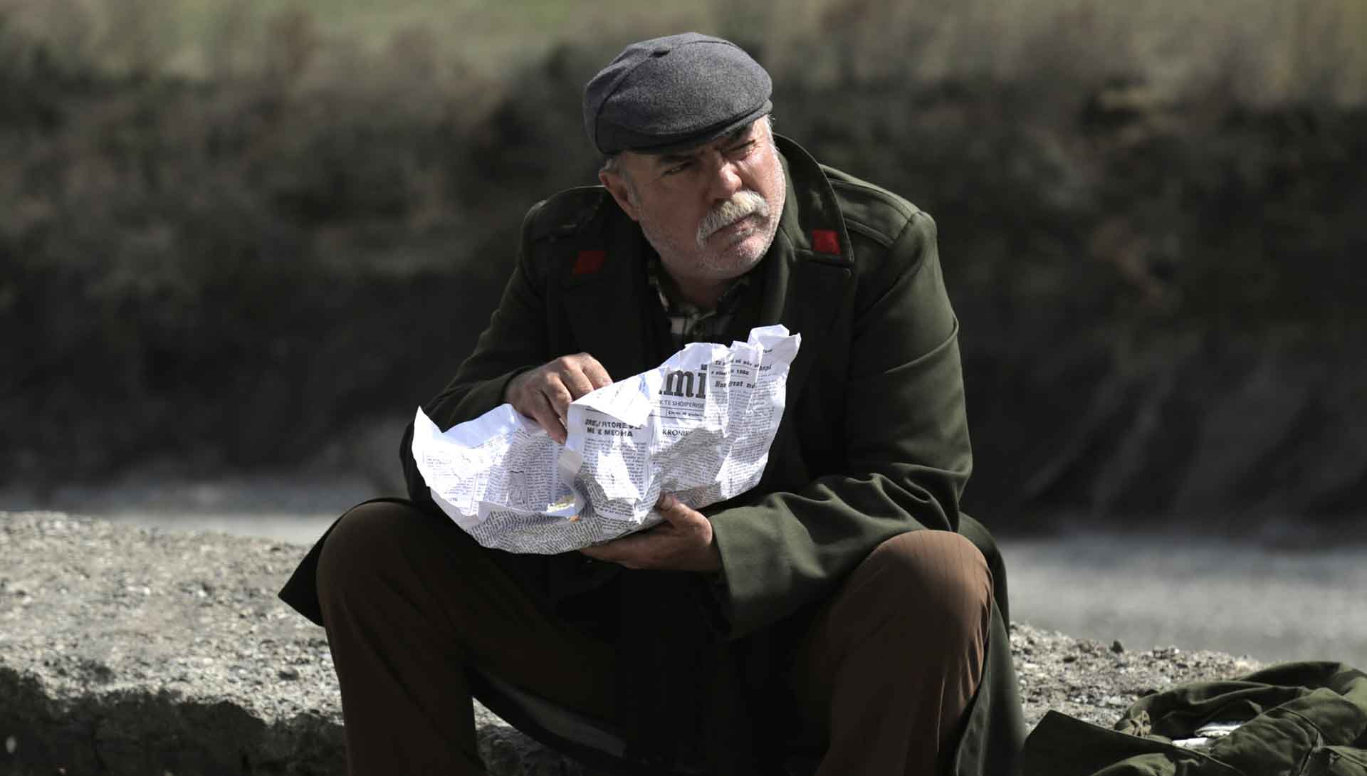 Un homme tient un journal. Extrait du film Le Dernier prisonnier de Bujar Alimani