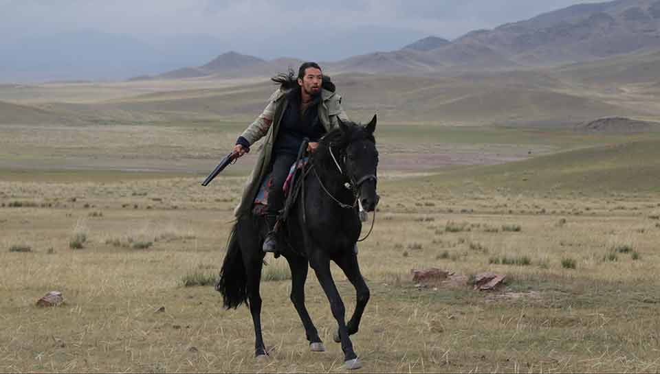 Un homme au galop sur un cheval, dans la montagne. Extrait du film 