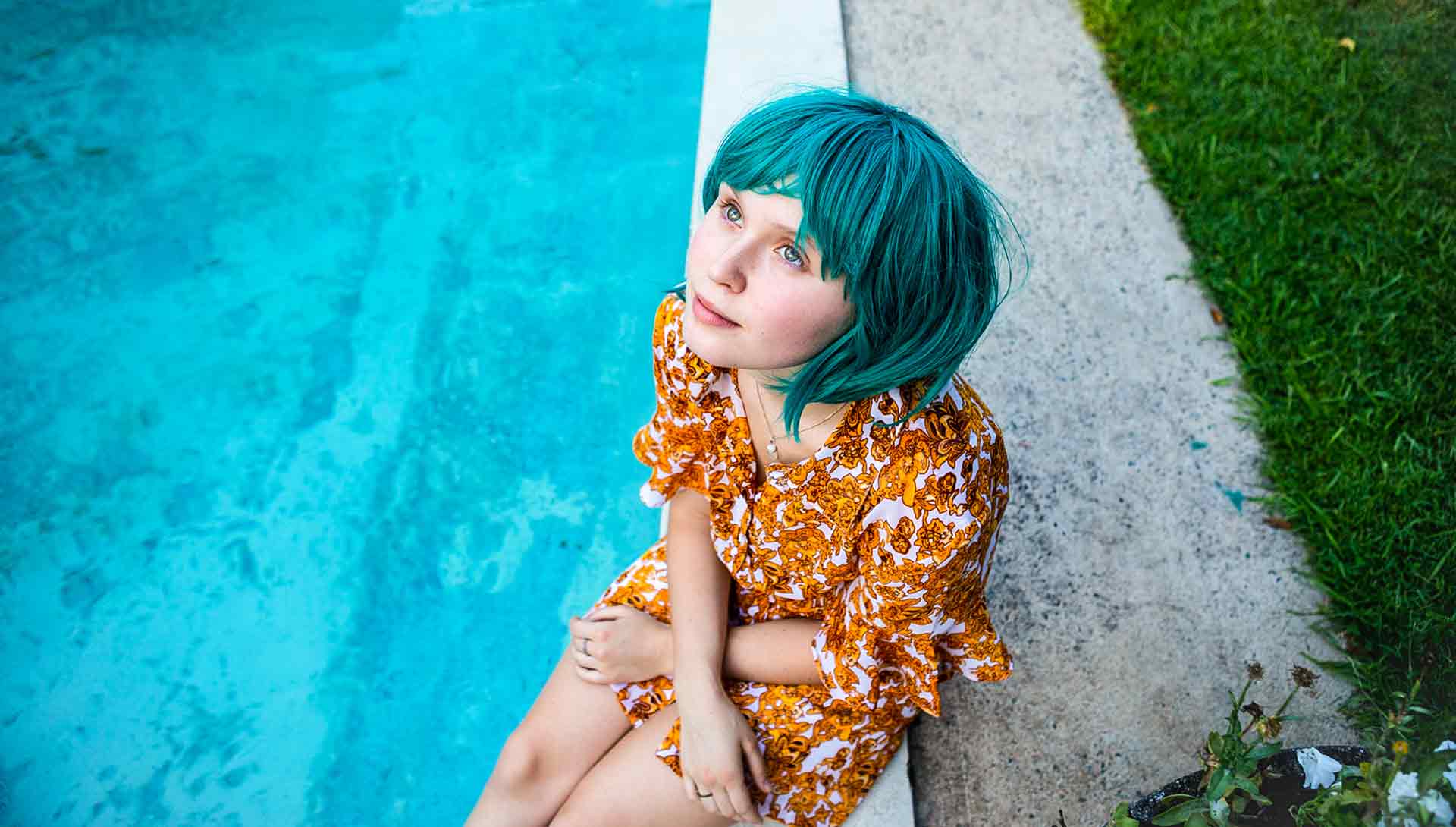 Jeune femme assise au bord d'une piscine les yeux rivés vers le ciel. Extrait du film 