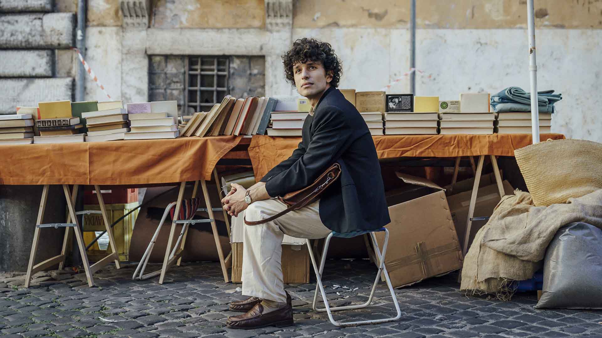 Un jeune homme est assis devant un stand de livre