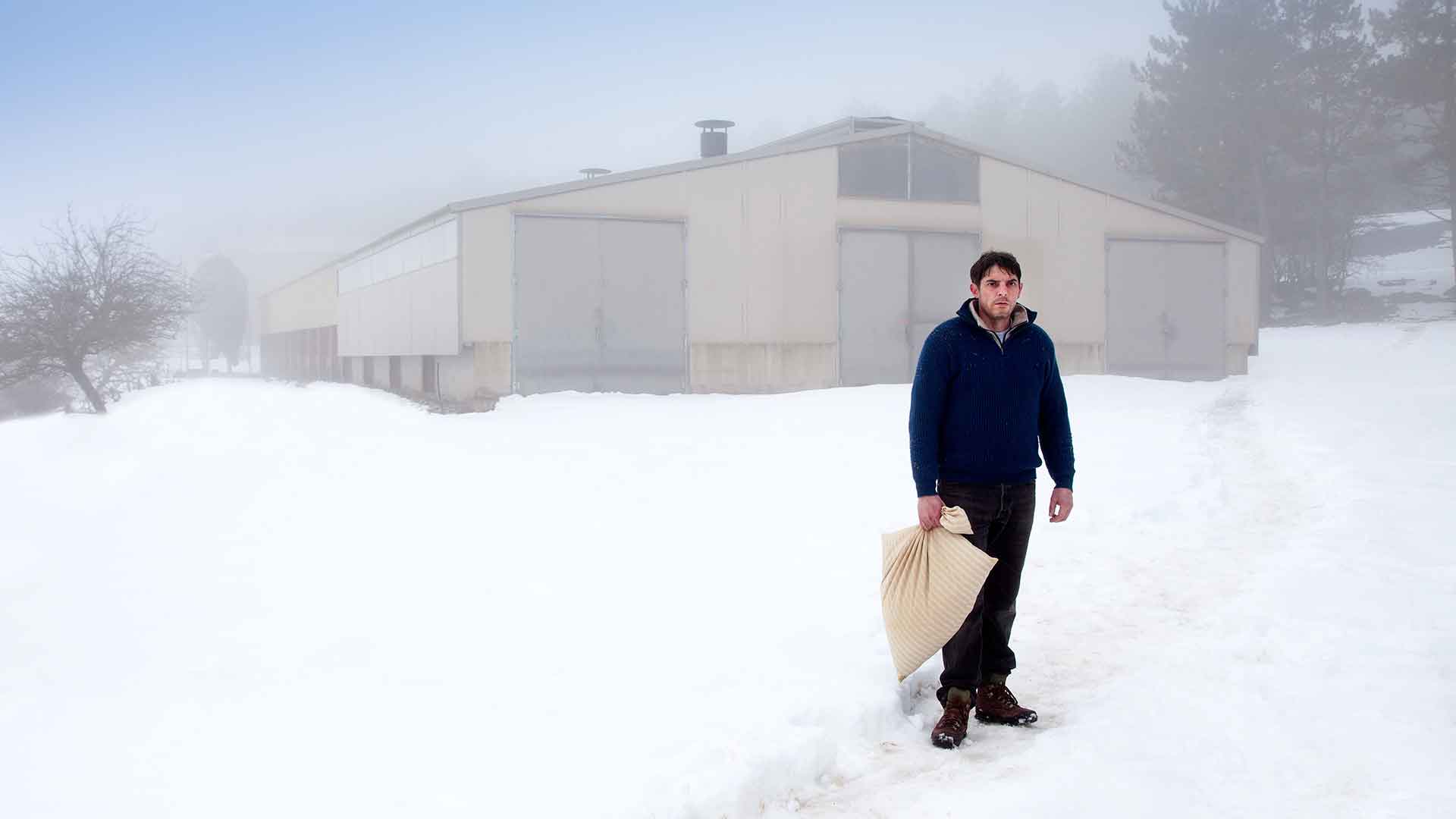 Un homme seul dans la neige tenant un sac