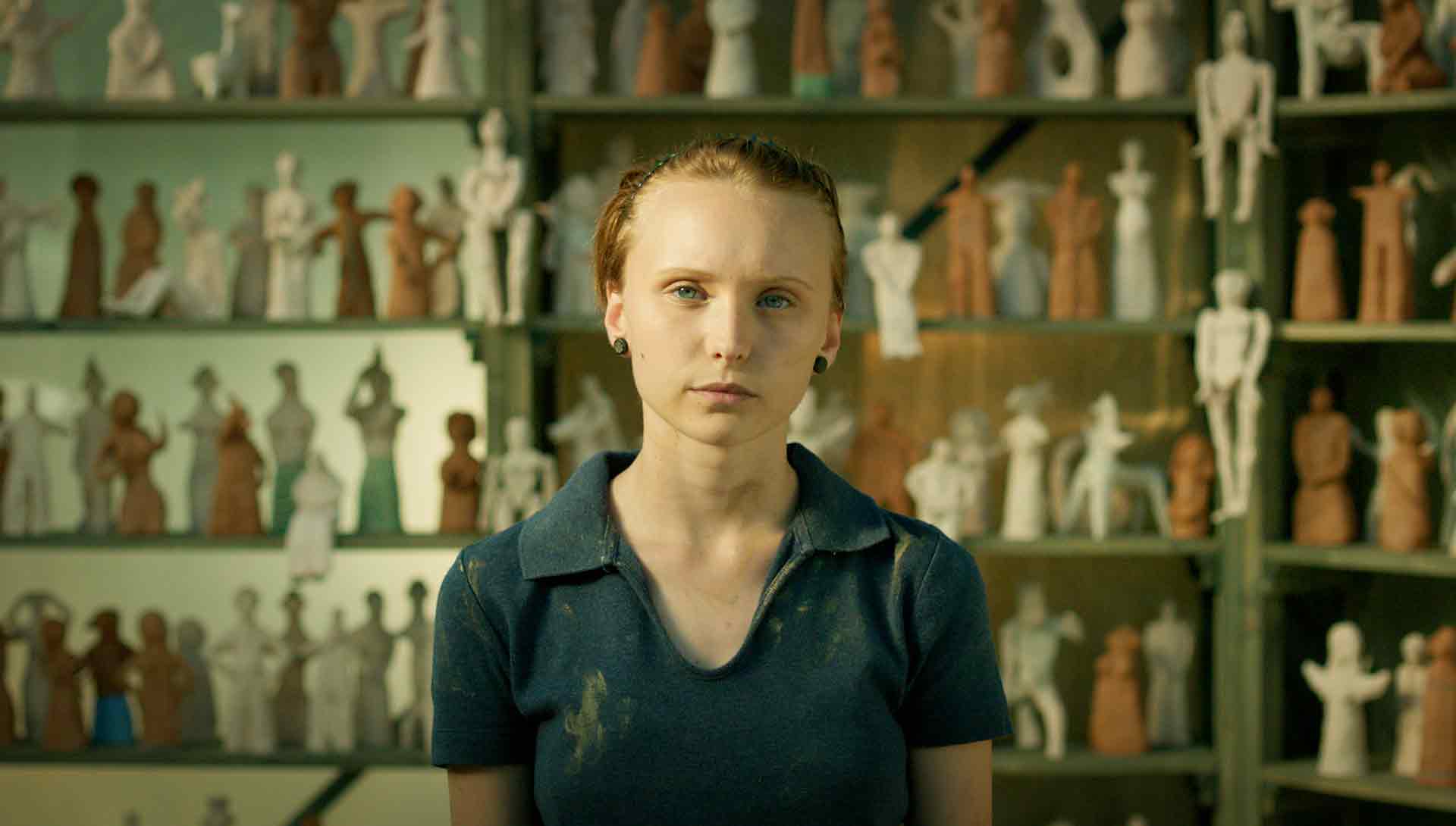 Une jeune femme devant un mur de figurine en argile. Extrait du film Sister de Svetla Tsotsorkova