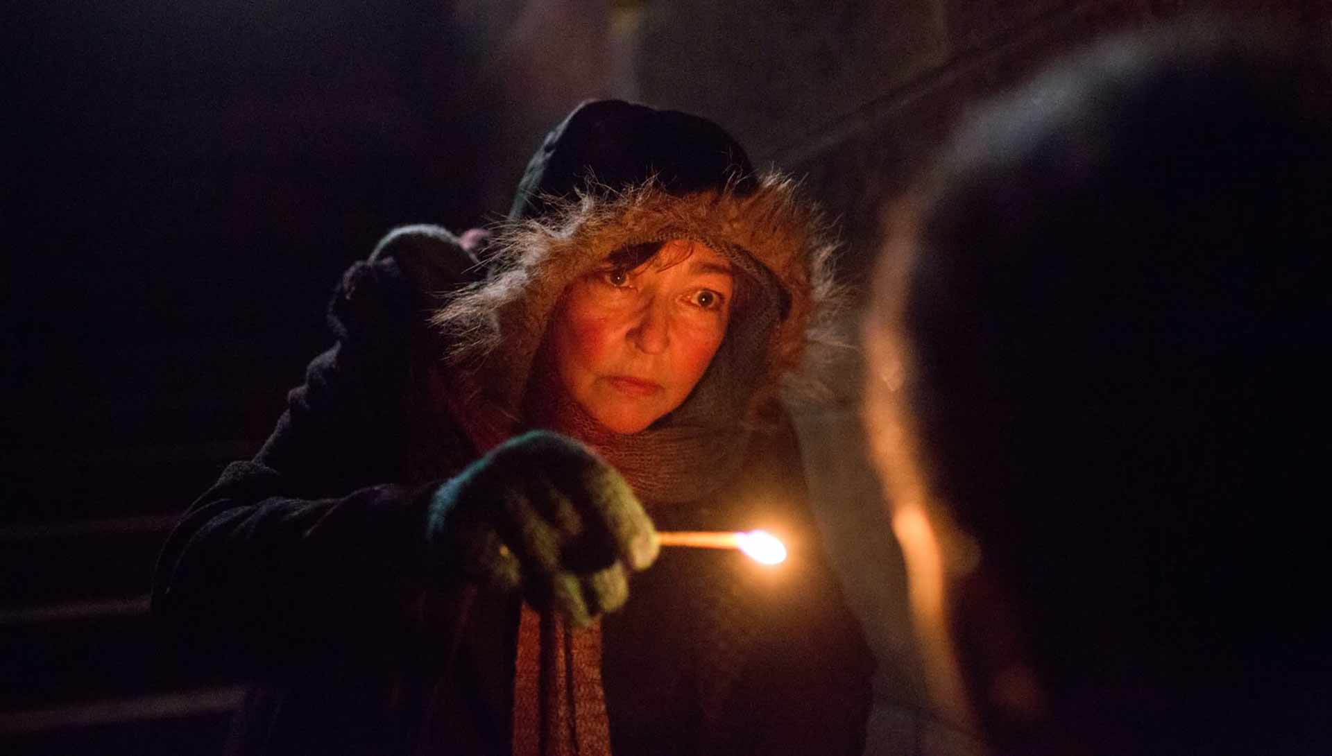 Une femme sans-abri tient une allumette. Extrait du film Sous les étoiles de Paris de Claus Drexel